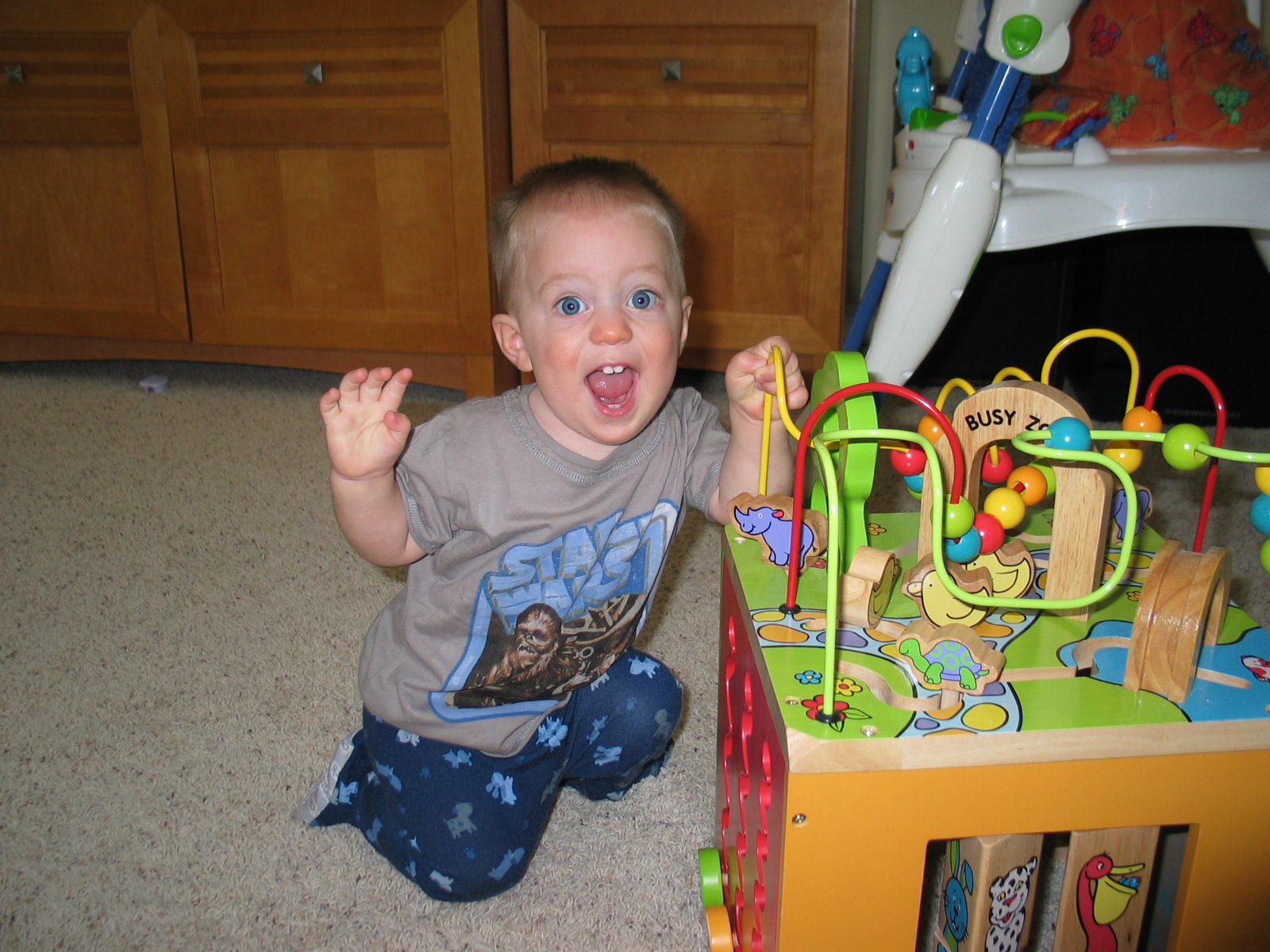 A baby boy with big blue eyes and two front teeth smiles big for the camera.
